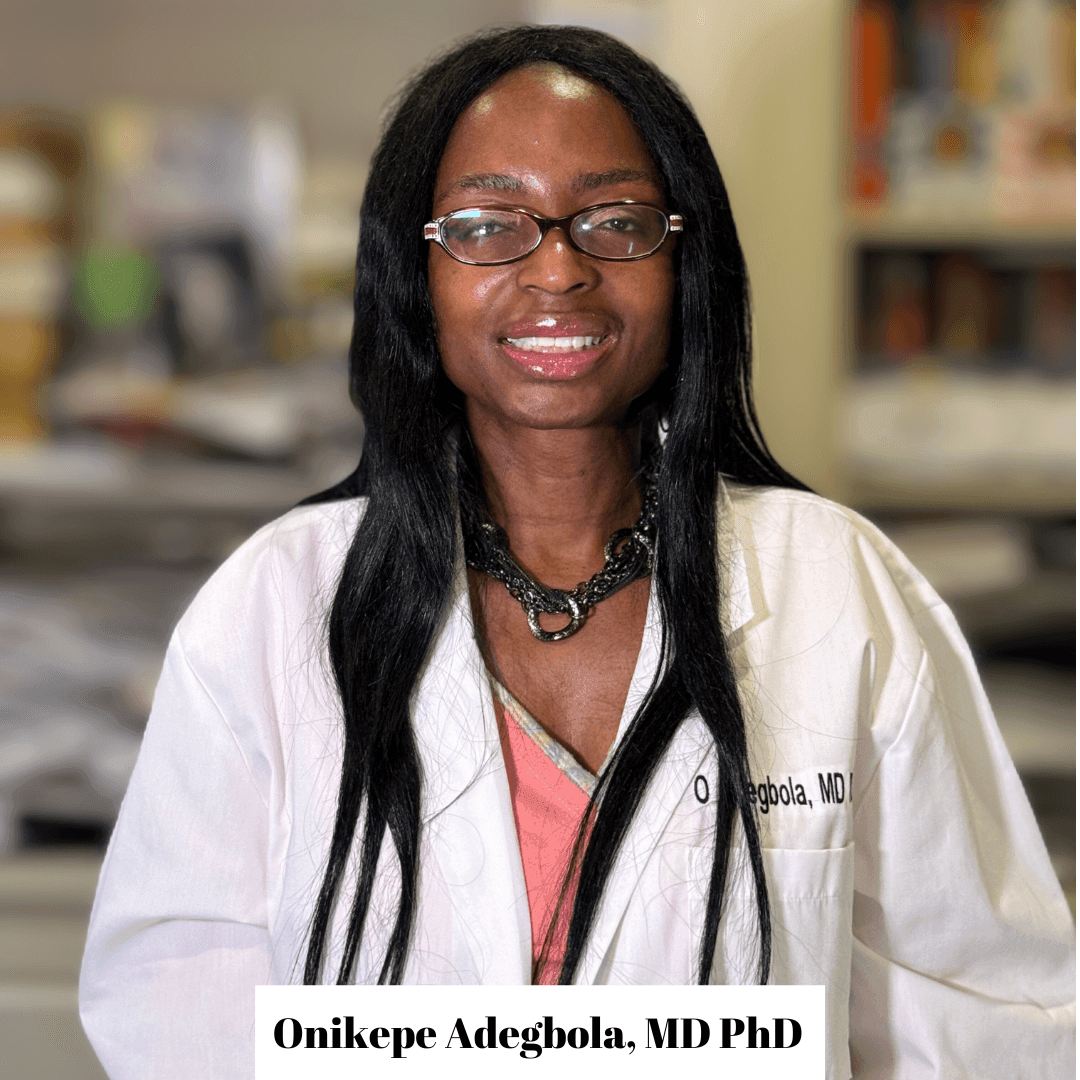 Person wearing a white lab coat standing in an office or laboratory setting.