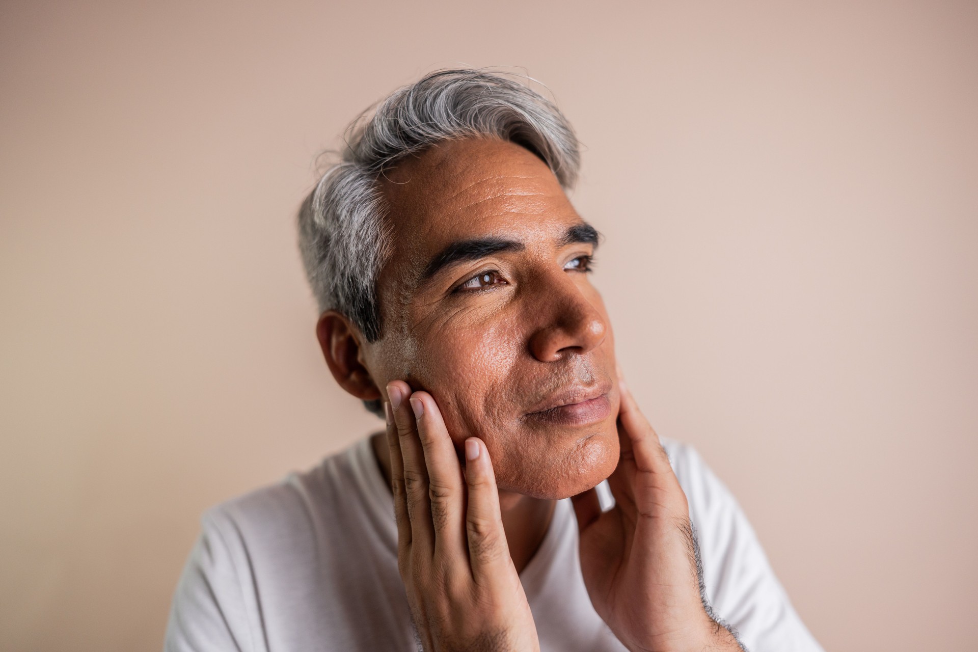 Mature man taking care of his skin applying cream on a studio shot